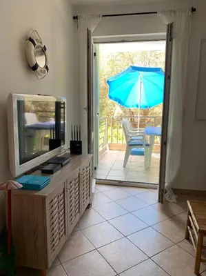 a living room with a television and an umbrella at Apartment Oliva, Rafailovici in Budva