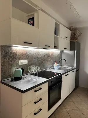 a kitchen with white cabinets and a counter with wine glasses at Apartment Oliva, Rafailovici in Budva