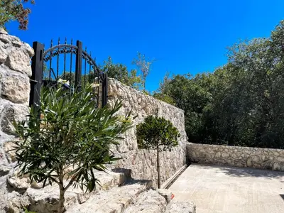 a stone wall with a black gate on it at Cozy Karuč Home in Cetinje
