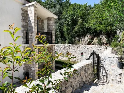a house with a stone wall and a fence at Cozy Karuč Home in Cetinje
