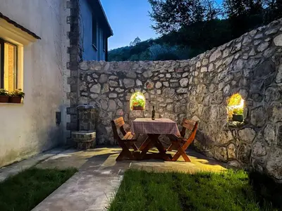 a table with two chairs and a stone wall at Cozy Karuč Home in Cetinje