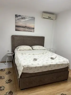 a bed in a bedroom with a picture on the wall at Centrum Apartman & Rooms in Ulcinj