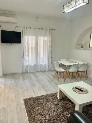 a white living room with a table and chairs at Centrum Apartman & Rooms in Ulcinj