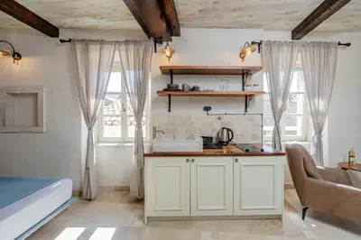 a kitchen with white cabinets in a room with windows at Casa Di Mino Old Town in Budva