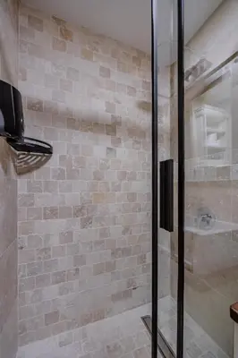 a bathroom with a glass shower with a brick wall at Casa Di Mino Old Town in Budva