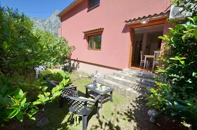 a pink house with a table and chairs in the yard at Apartments Dada in Kotor