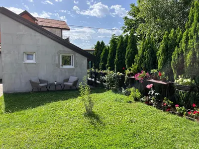 a yard with two chairs and a fence and flowers at Guest house TAK in Cetinje