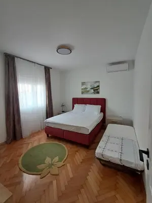 a bedroom with a bed and a couch and a rug at HOME POINT Apartment in Podgorica
