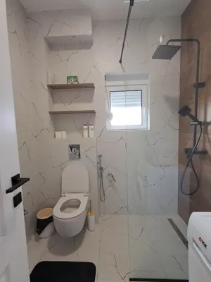 a white bathroom with a toilet and a window at HOME POINT Apartment in Podgorica