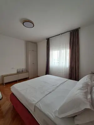 a bedroom with a large white bed with a window at HOME POINT Apartment in Podgorica