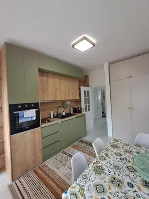 a kitchen with green cabinets and a table with chairs at HOME POINT Apartment in Podgorica