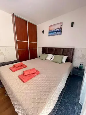 a bedroom with a large bed with two red towels on it at Apartment Rafailovici in Rafailovici