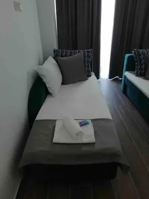 a small bed in a room with a couch at Sea view dobra voda in Dobra Voda