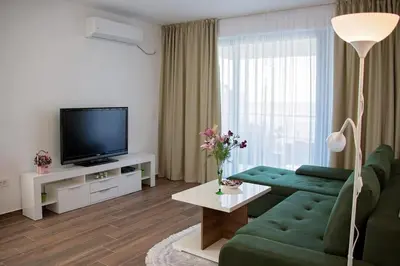 a living room with a green couch and a television at Sea view dobra voda in Dobra Voda