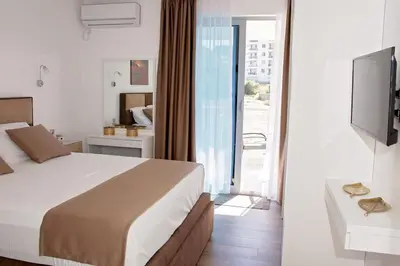 a hotel room with a bed and a television at Sea view dobra voda in Dobra Voda
