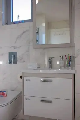 a white bathroom with a sink and a mirror at Sea view dobra voda in Dobra Voda