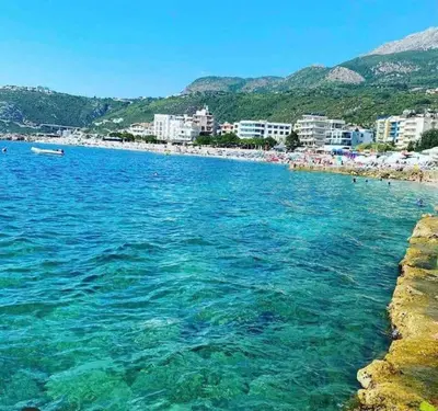 a large body of water with a beach and buildings at Sea view dobra voda in Dobra Voda