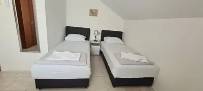 two twin beds in a room with a mirror at Guest House Andrea in Budva