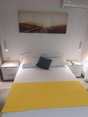 a bedroom with a large bed with a yellow blanket at Apartments NIKOS FAMILY in Ulcinj
