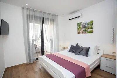 a bedroom with a large white bed and a window at Apartments NIKOS FAMILY in Ulcinj
