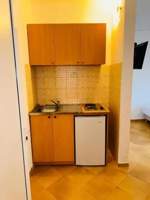 a small kitchen with wooden cabinets and a sink at ADO Apartmani Ulcinj Velika Plaza Donji Stoj in Donji Štoj