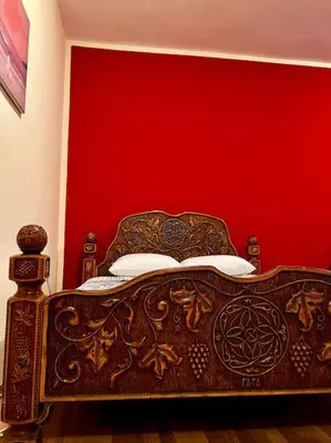 a bedroom with a wooden bed with a red wall at City Center Cozy Studio in Podgorica