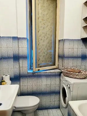 a bathroom with a toilet a sink and a washing machine at City Center Cozy Studio in Podgorica