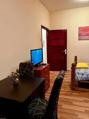 a living room with a television and a table and chairs at City Center Cozy Studio in Podgorica