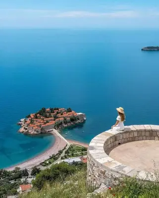 a woman sitting on the edge of a wall looking at the ocean at Panorama Milocer Apartments in Budva