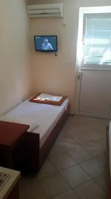 a small room with a bed and a tv on the wall at Guest house Rade Z in Budva
