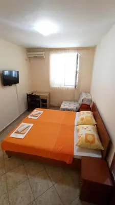 a bedroom with a large bed with an orange bedspread at Guest house Rade Z in Budva