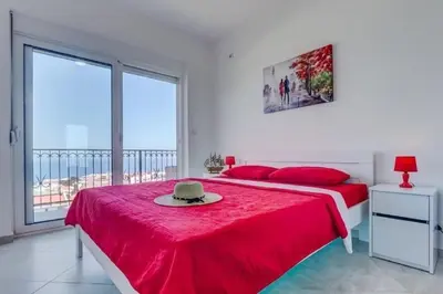 a bedroom with a red bed with a hat on it at MarBok Apartments with SeaView in Utjeha