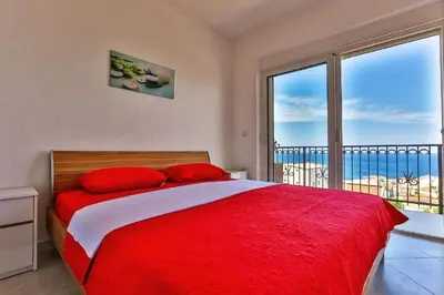 a bedroom with a red bed and a large window at MarBok Apartments with SeaView in Utjeha