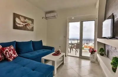 a living room with a blue couch and a balcony at MarBok Apartments with SeaView in Utjeha