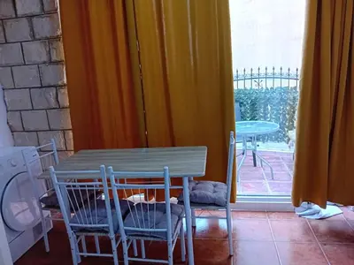 a table and chairs in a room with a window at Mota saste lux in Sveti Stefan