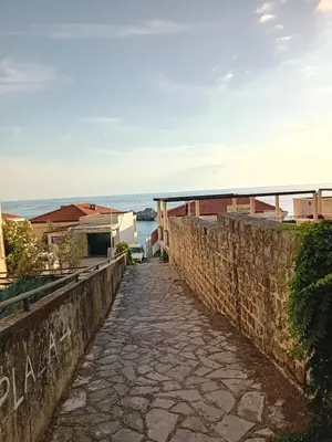 a stone path next to a wall with the ocean in the background at Mota saste lux in Sveti Stefan