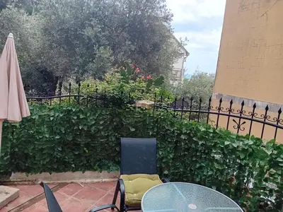 a patio with a table and an umbrella and a hedge at Mota saste lux in Sveti Stefan