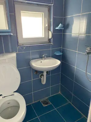 a blue tiled bathroom with a toilet and a sink at Апартаменты in Sutomore