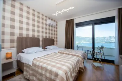 a hotel room with two beds and a large window at Villa Maya in Budva