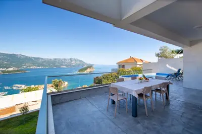 a dining table on a balcony with a view of the ocean at Villa Maya in Budva