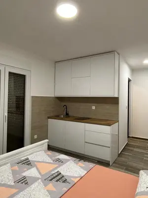 an empty kitchen with white cabinets and a sink at NNL Apartments in Sutomore