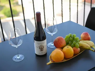 a bottle of wine and a plate of fruit on a table at Merlin Prestige Apartments in Budva