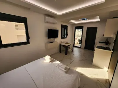 a bedroom with a white bed and a kitchen at Merlin Prestige Apartments in Budva