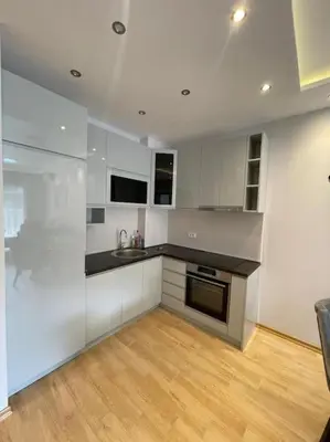 a kitchen with white cabinets and a wooden floor at Old barkery, the most exclusive complex in Budva in Budva