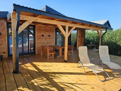 a wooden deck with a table and chairs on it at Estuary Cottage Ada Bojana in Ulcinj