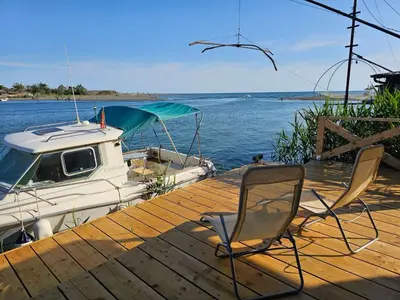 a dock with a chair and a boat on the water at Estuary Cottage Ada Bojana in Ulcinj