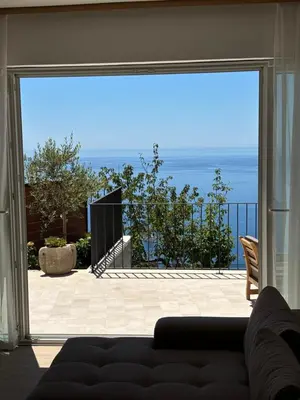 a living room with a couch and a large window at Villa Žukovica in Petrovac na Moru