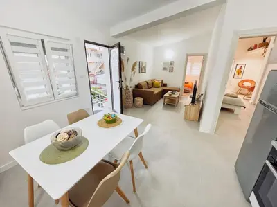 a dining room and living room with a white table and chairs at Apartman DE LUX RADIVOJEVIĆ in Sutomore