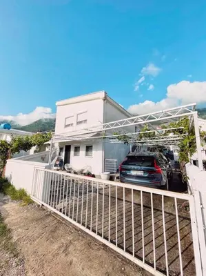 a house with a car parked in a garage at Apartman DE LUX RADIVOJEVIĆ in Sutomore