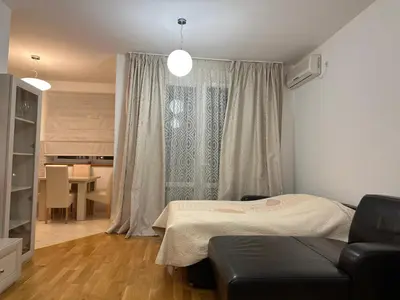 a bedroom with a bed and a couch in front of a window at Light Bar Apartment in Bar